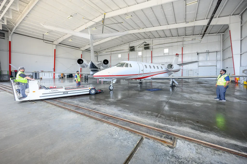 Employees moving a corporate jet into the hangar at Texarkana Regional Airport