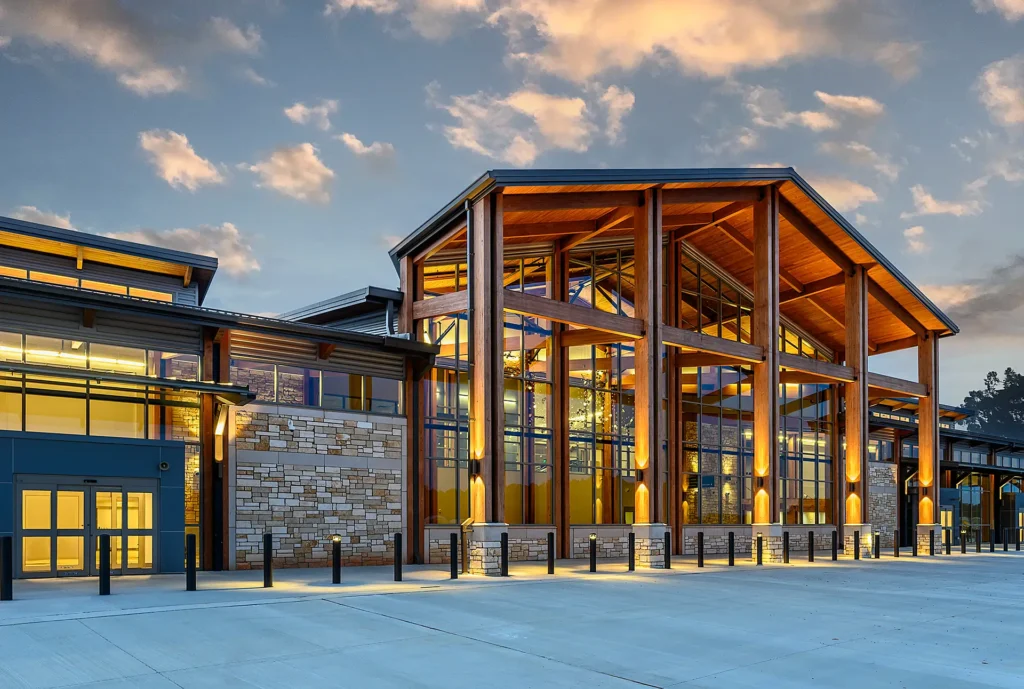The new TXK Airport terminal building at sunrise, with beautiful outdoor lighting, tall ceilings, and wood treatments ready to welcome passengers.