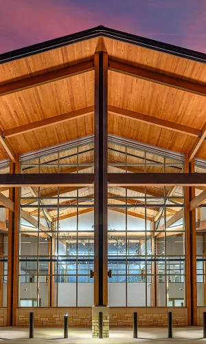 A beautiful new terminal building with a large wood overhand and tall glass windows at sunset